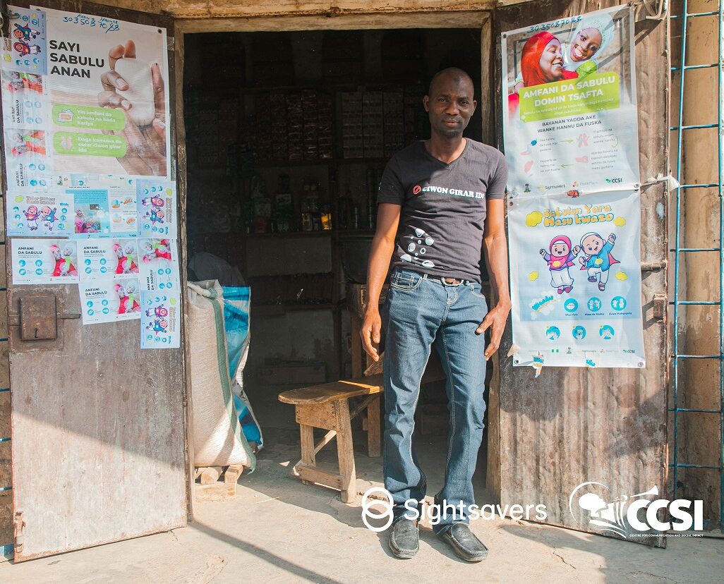 Kabiru Hassan, a soap vendor, poses in front of his shop.